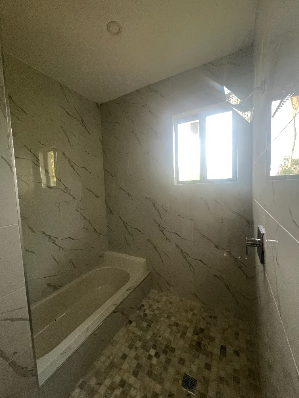 Bathtub and walk-in shower with marble-pattern wall tile