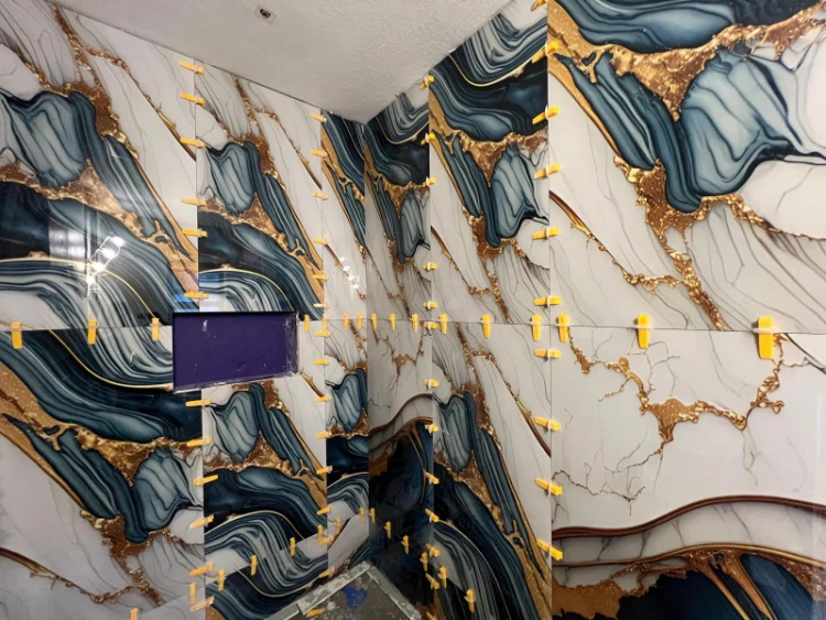 Blue, gold and white shower wall tiles during installation