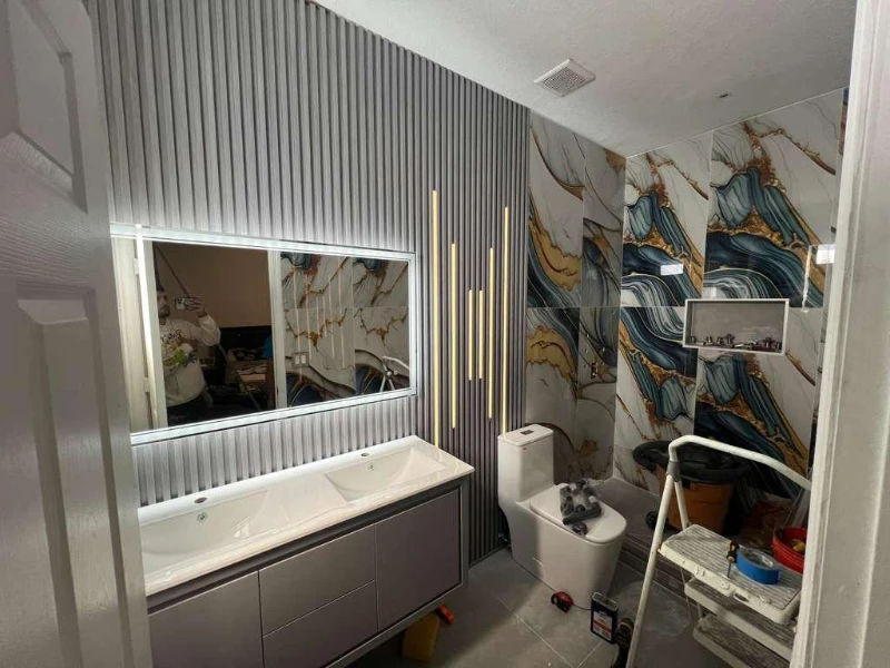Bathroom vanity with illuminated mirror and patterned shower walls