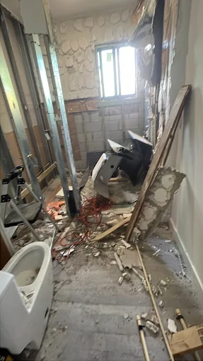 Bathroom demolition with exposed wall framing and removed fixtures