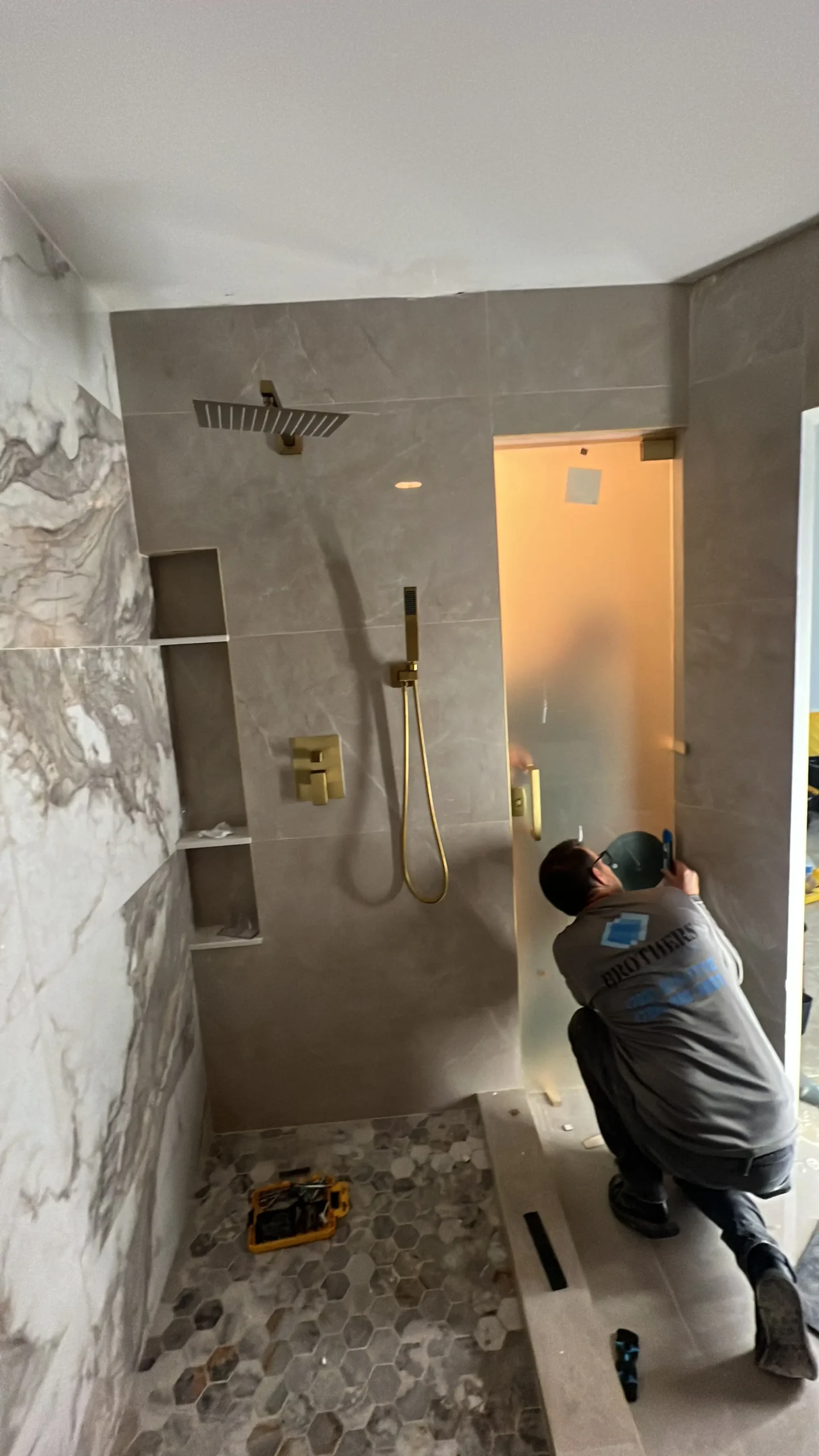 Worker installing tile beside a bathroom shower