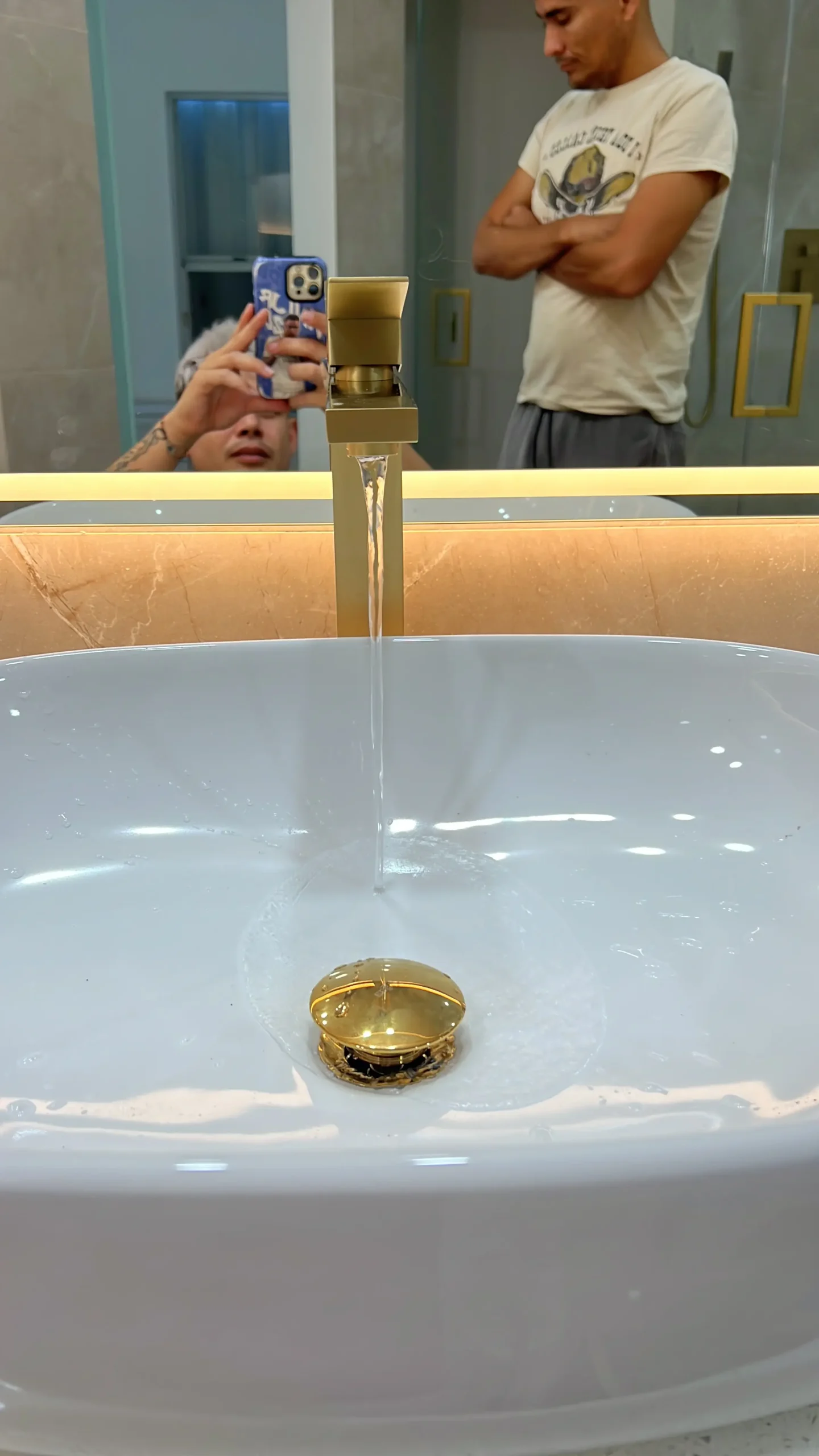 White vessel sink with gold faucet and illuminated mirror