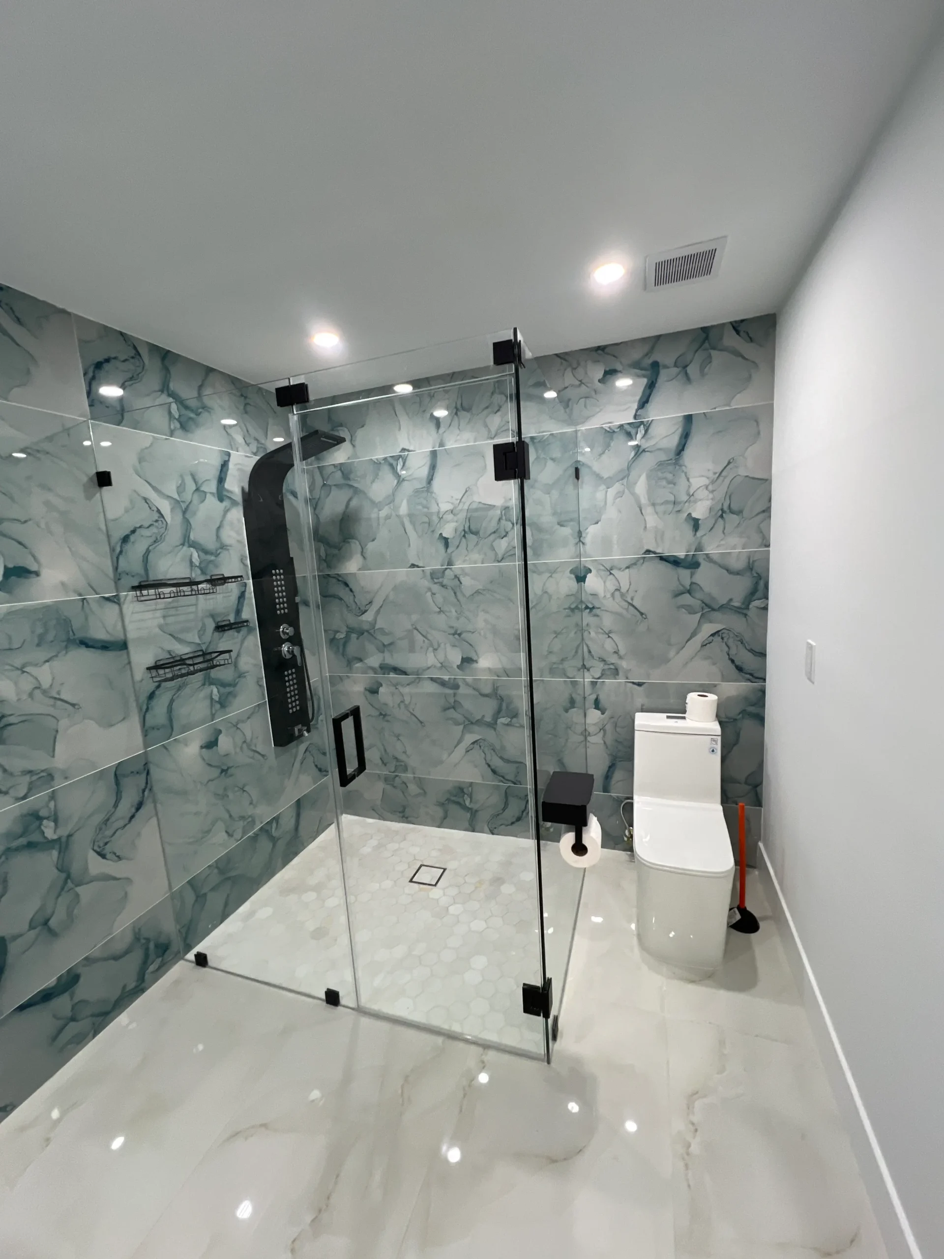 Bathroom with glass shower enclosure and green marble-pattern tile